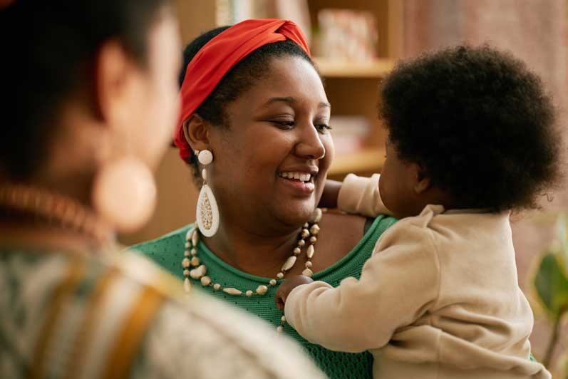 smiling-mother-holding-baby-while-chatting-with-fa-2025-05-31-23-26-19-utc-aspect-ratio-700-525